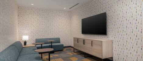 Una habitación de hotel moderna con un sofá modular, una mesita, un armario y un televisor de pantalla plana montado en la pared.