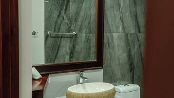 Un baño con pared de mármol, un lavabo redondo, un espejo y un perchero para toallas.