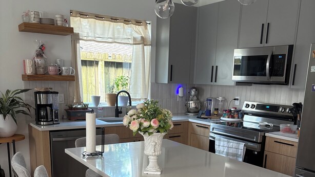 Una cocina moderna con una isla central, taburetes de bar, una cafetera y un microondas.