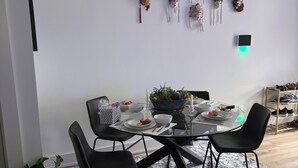 Un comedor con una mesa redonda, sillas negras, una planta en maceta y adornos en la pared.