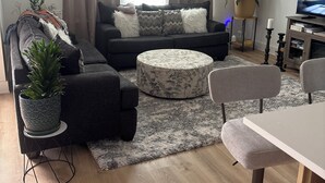 Una sala de estar moderna con un sofá, reposapiés y un comedor con una mesa y sillas.