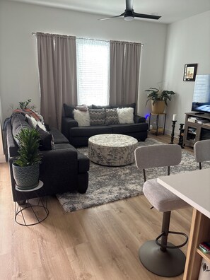 A modern living room with a sofa, ottoman, and a dining area with a table and chairs. - Fabulous 3-bedroom/3 bath apartment with Central Heating &AC in Houston (Houston)