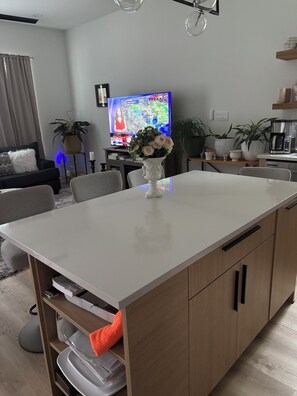 A modern living room with a white dining table, a sofa, a TV, and potted plants. - Fabulous 3-bedroom/3 bath apartment with Central Heating &AC in Houston (Houston)