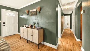 A hallway with wooden flooring, a light-colored cabinet, and green walls. - Jville Gem- Walk downtown (Jacksonville)