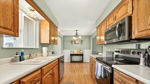 A kitchen with wooden cabinets, a microwave, an oven, and a sink. - Jville Gem- Walk downtown (Jacksonville)