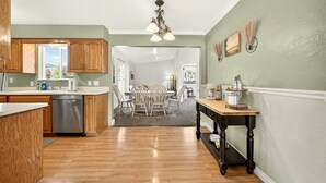 A kitchen with wooden cabinets, a dishwasher, and a dining area with a table and chairs. - Jville Gem- Walk downtown (Jacksonville)