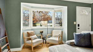 A room with a bay window, two armchairs, a small table with a globe, and a door. - Jville Gem- Walk downtown (Jacksonville)