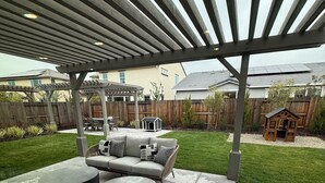 A covered patio area with a built-in seating arrangement, a small dog house, and a wooden playhouse.