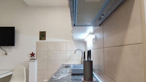 A modern kitchen with a black countertop, a built-in stove, a sink, and a range hood. - Comfort Apartments Igalo 60 m From the Sea (Igalo)