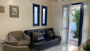 Un salon avec un canapé en cuir noir, un fauteuil beige et une petite table sur laquelle est posée une plante.