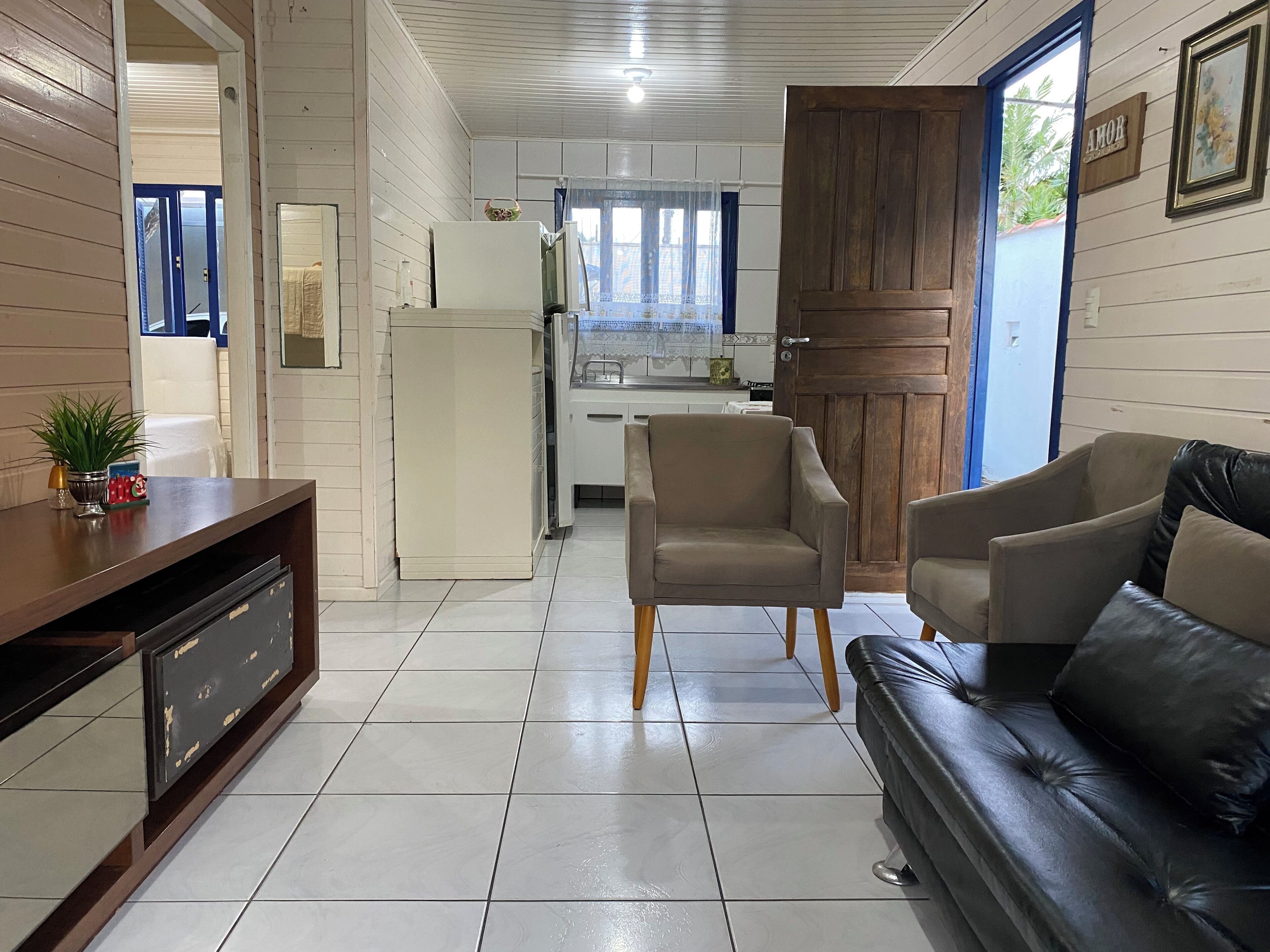 Una sala de estar con un sofá, televisión y una cocina al fondo.