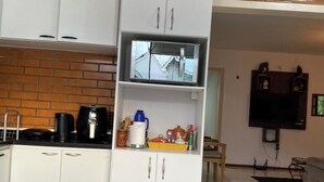Une cuisine avec des meubles blancs, une machine à café et un four à micro-ondes.