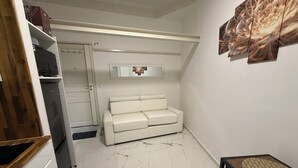 Une pièce avec un sol en marbre blanc, un canapé blanc, une table en bois et un miroir au mur.