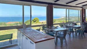 A dining area with large windows overlooking a coastal landscape.