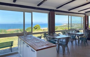 Uma área de refeições com grandes janelas com vista para a paisagem costeira.