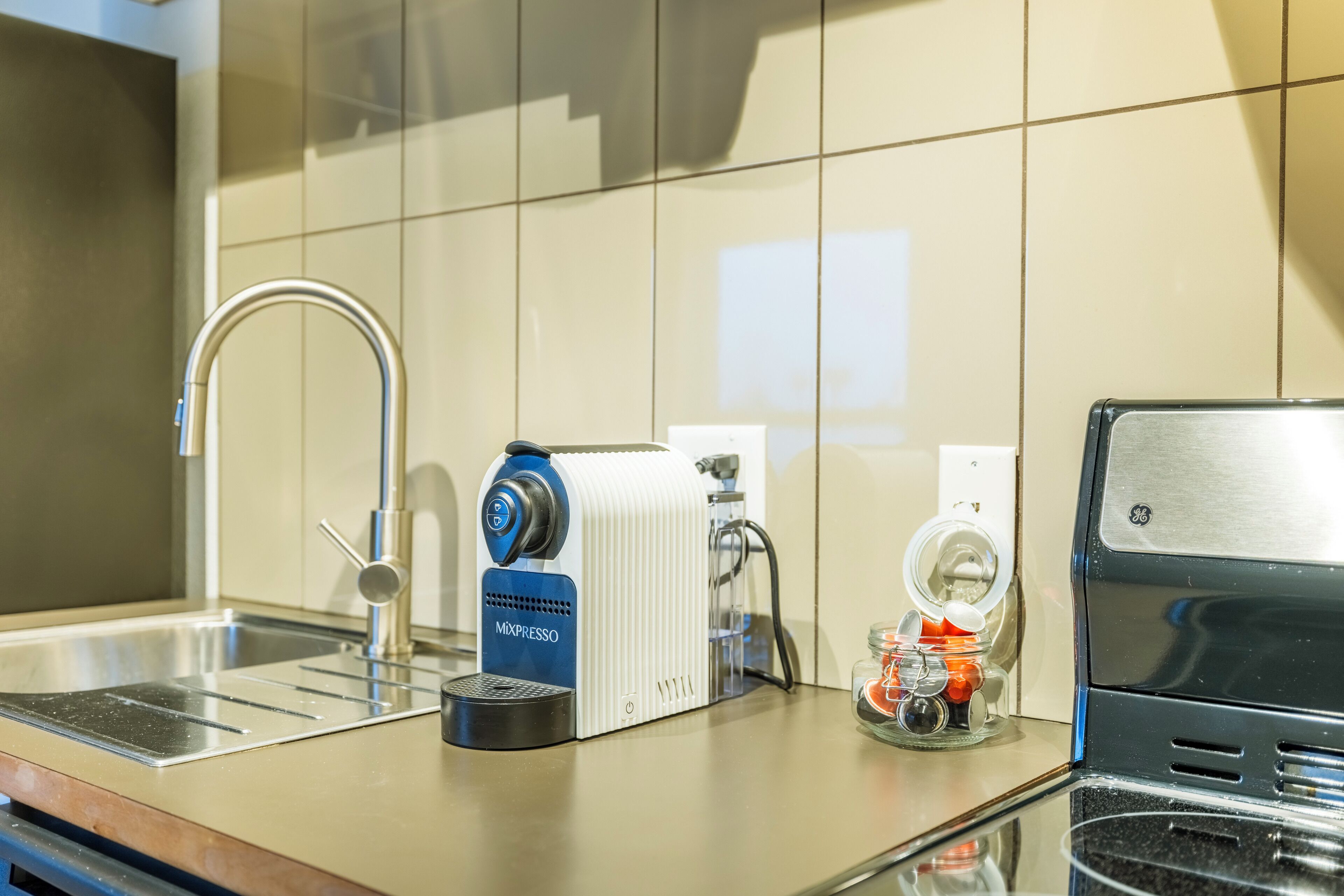 Una cocina con cafetera, fregadero y microondas.