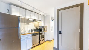 A modern kitchen with white cabinets, stainless steel appliances, and a wooden countertop. - Urban Brick Loft Studio • Ride to Trails • Walk to Dining, Shops & Nightlife (Rogers)