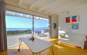 Une chambre moderne dotée d’une grande porte-fenêtre coulissante donnant sur une terrasse avec vue sur la mer.