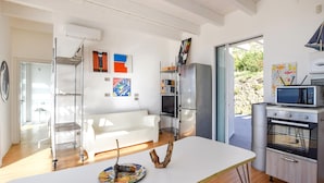 A modern kitchen with a white countertop, stainless steel appliances, and artwork on the walls.
