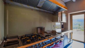 Una cocina con una estufa grande, un ventanal con vistas y una campana extractora.