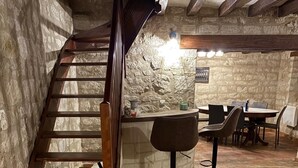 A rustic interior with a wooden staircase, hexagonal tiled floor, stone walls, and a bar area with stools. - La Bergerie des vignes" country house shared with sheep. (Bourgueil)