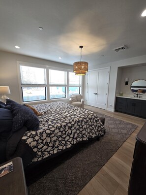 Une chambre à coucher avec un lit, une chaise, un bureau, une commode et une fenêtre.