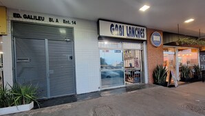 A storefront with a closed metal shutter and a sign reading "GABI LANCHE'S". - Studio apartment with movement, elevator, and open balcony in Asa Norte. (Brasília)