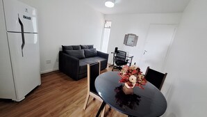 A compact living space with a kitchenette, a sofa, a dining table with chairs, and a ceiling light. - Studio apartment with movement, elevator, and open balcony in Asa Norte. (Brasília)
