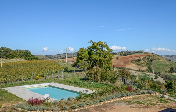 A pool surrounded by a landscaped garden with a vineyard in the background. - Amazing home in Cinigiano (Cinigiano)