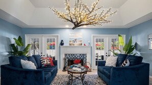 Een woonkamer met twee blauwe banken, een kamerbreed tapijt met dessin, een open haard en een decoratieve boomlamp.