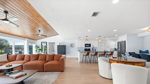 A spacious living area with a brown sectional sofa, a white armchair, and a wooden dining table. - Clover Vacation Homes: Snead Island: Luxury 4 BR, Heated Pool, Beaches (Palmetto)