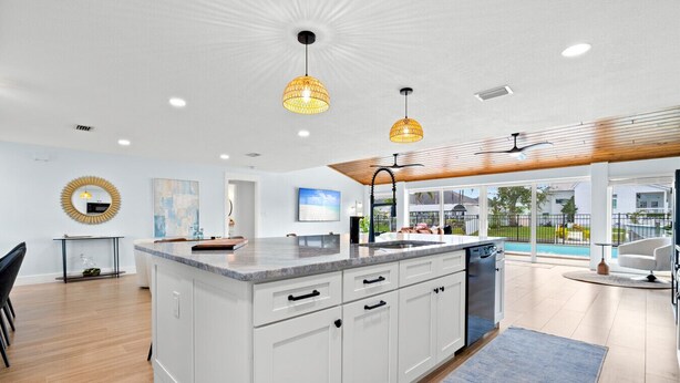 A modern kitchen with a large island, white cabinetry, and pendant lighting. - Clover Vacation Homes: Snead Island: Luxury 4 BR, Heated Pool, Beaches (Palmetto)