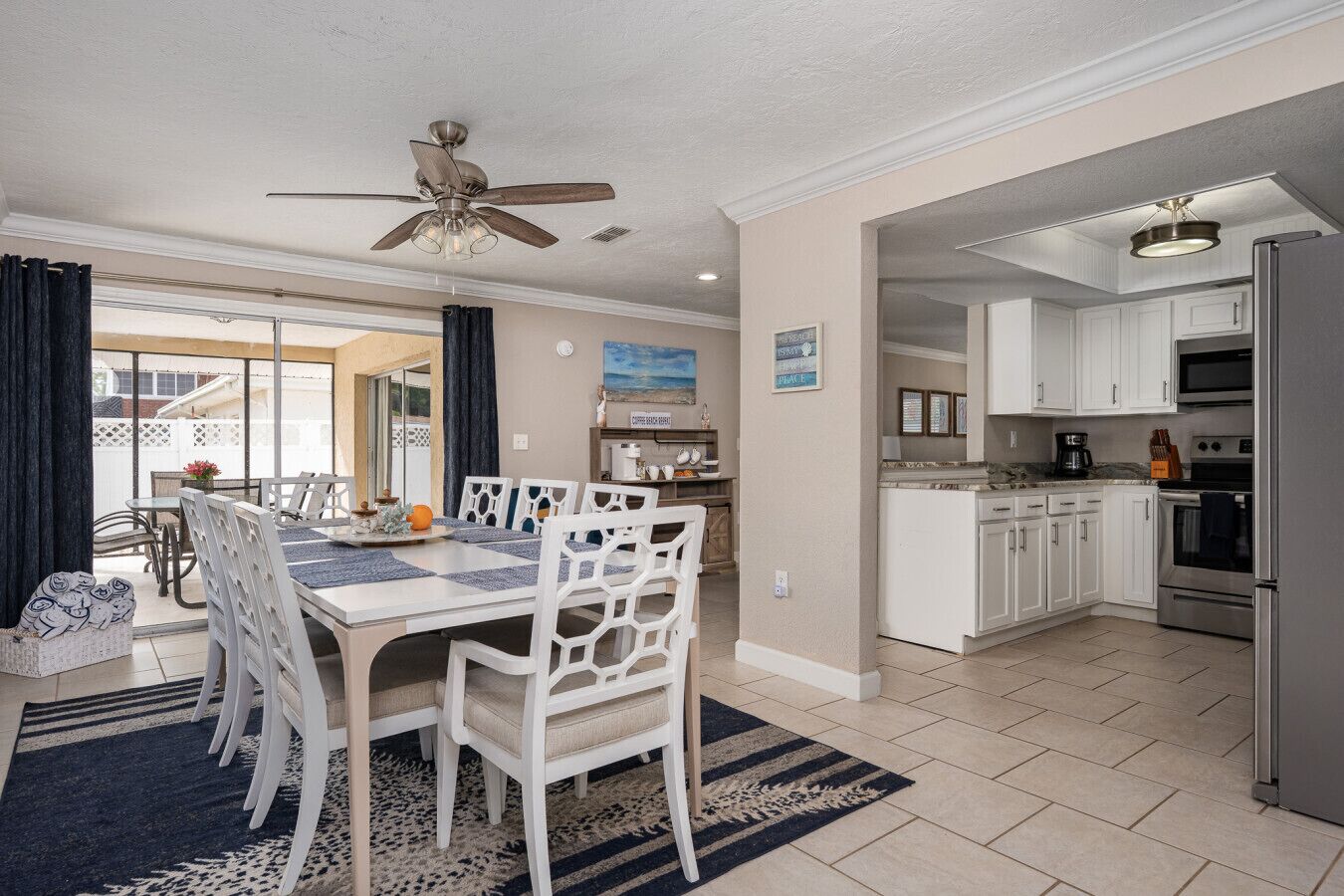A spacious kitchen with white cabinets, a stainless steel refrigerator, and a dining area with a table and chairs.