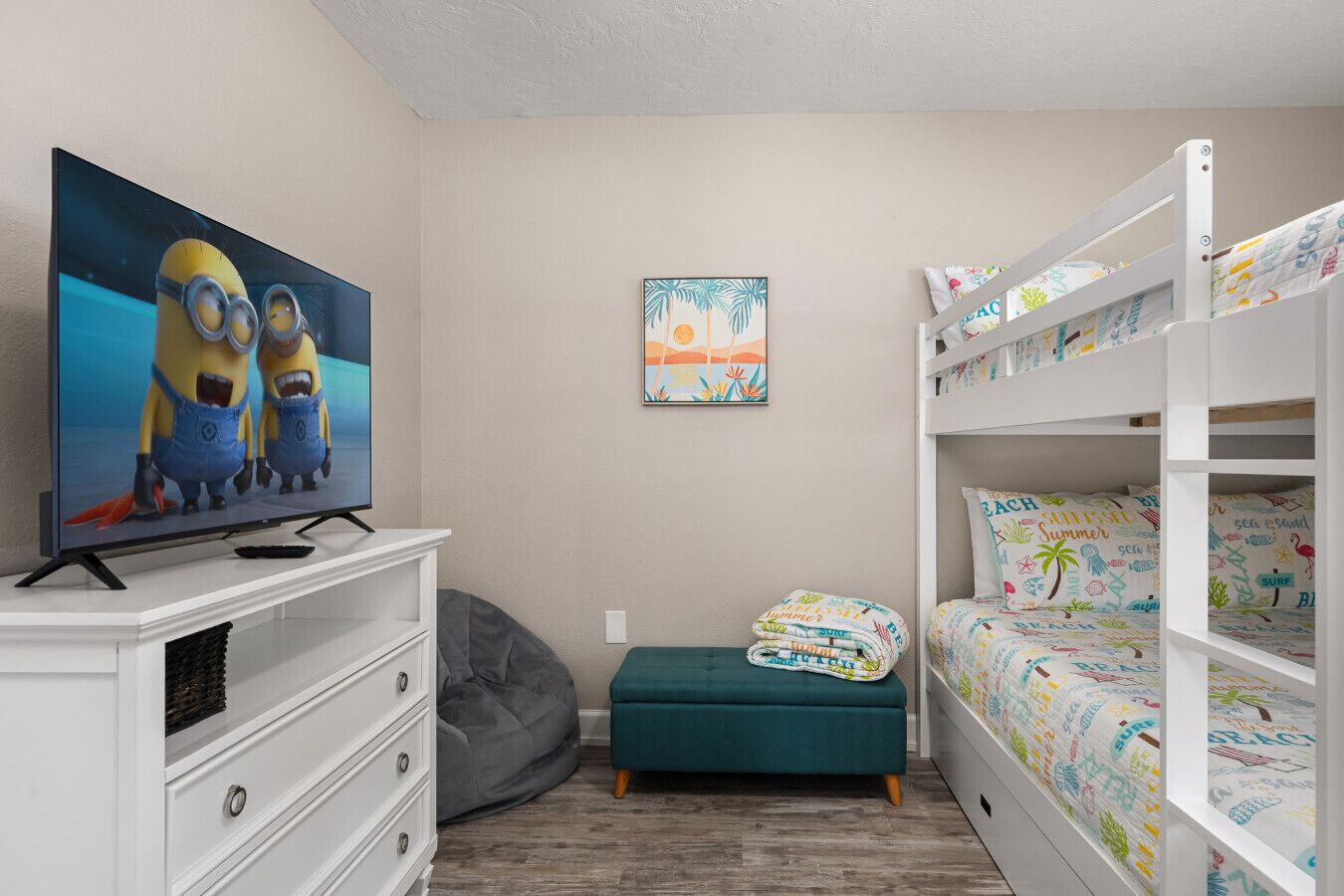 A bedroom with a TV, bunk beds, a bean bag, and a wall art piece.