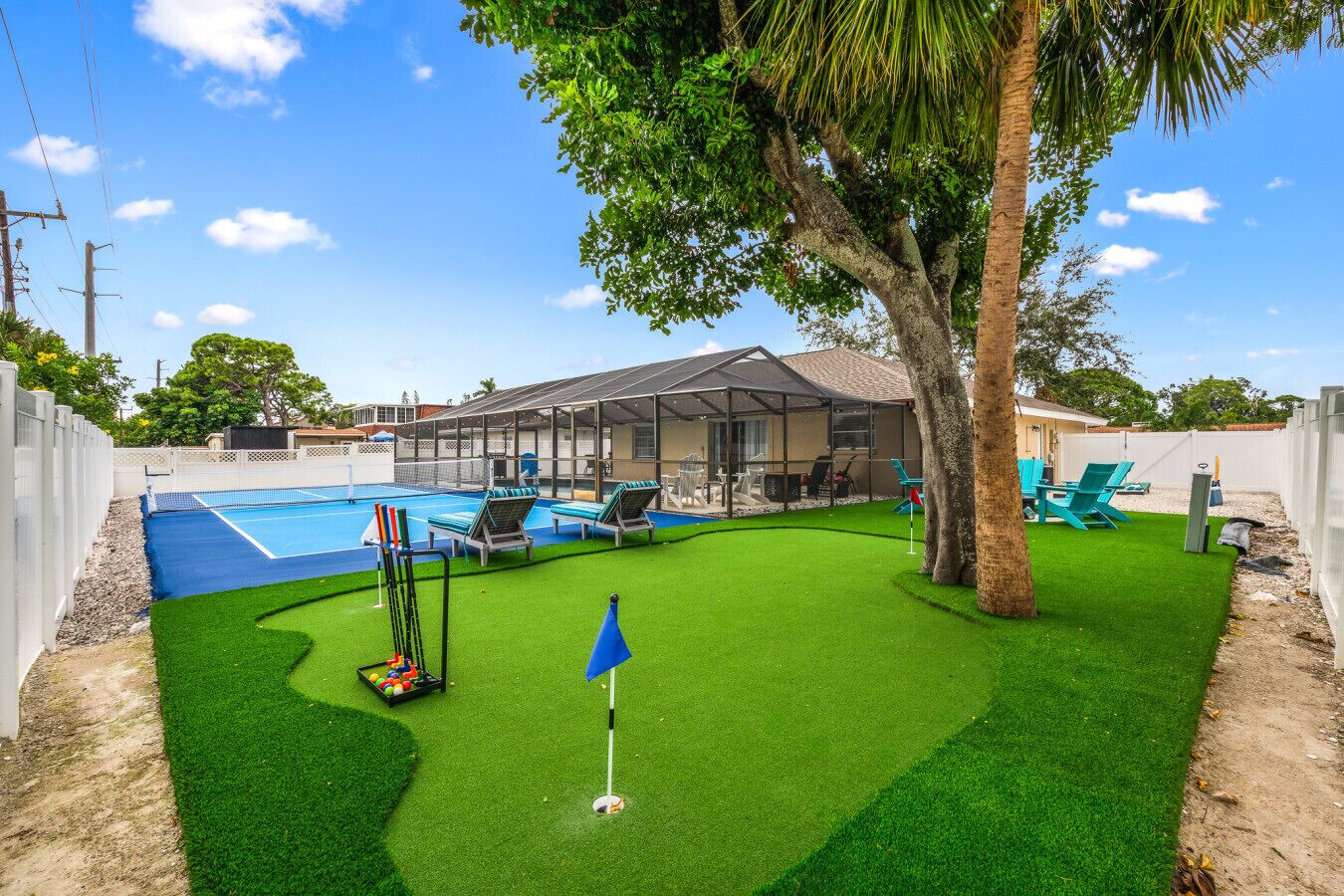En trädgård med pool, konstgräs, en täckt uteplats och en golfgreen.