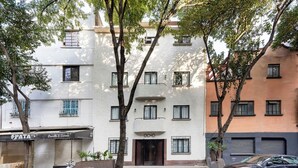 A multi-story building with a white facade, a brown door, and a sign that reads "OPATA". - Baranda OCHO By Smart W (Mexico City)