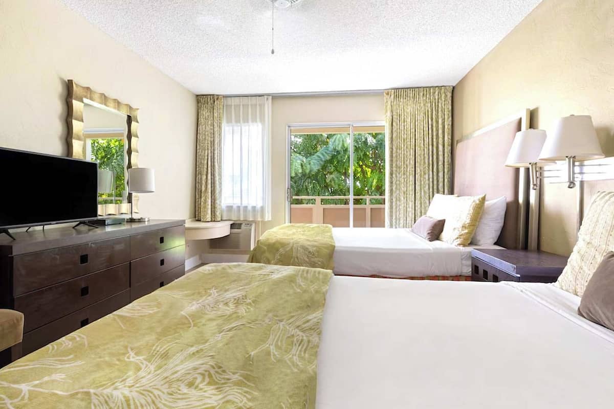 Habitación de hotel con dos camas, un televisor, un escritorio y una ventana con cortinas.