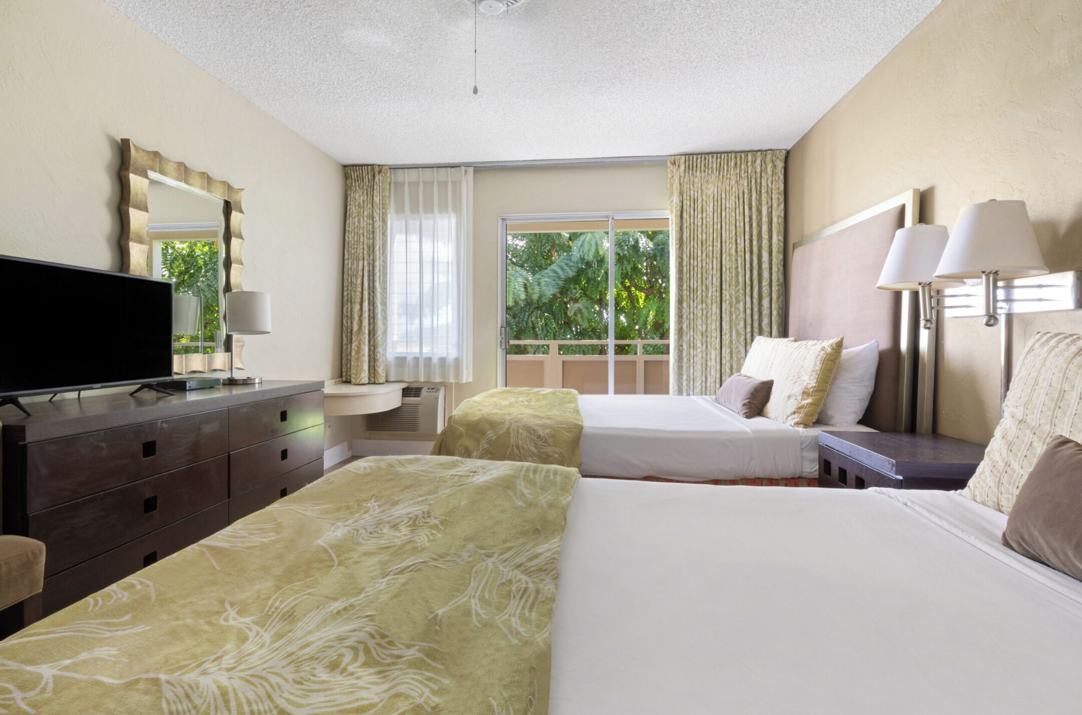 A hotel room with two beds, a flat-screen TV, a dresser, and a window with curtains.