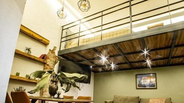 Un grand espace de vie comprenant une table à manger, des chaises, un canapé et une table basse. Un escalier mène à un niveau supérieur.