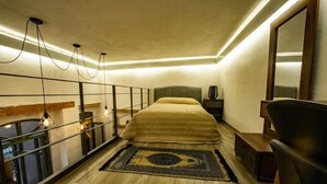 Une chambre à coucher comprenant un lit, une table de chevet, une chaise et un grand miroir.