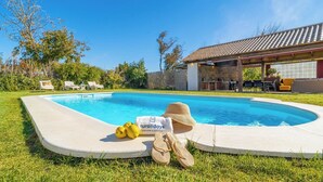 Uma piscina com um letreiro escrito 'ruraldayz', um chapéu e limões na grama.