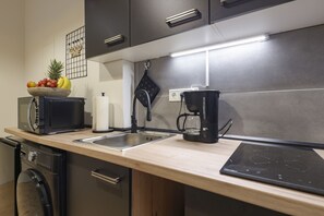 Une cuisine moderne avec un plan de travail en bois, une machine à café, un grille-pain et un panier à fruits.