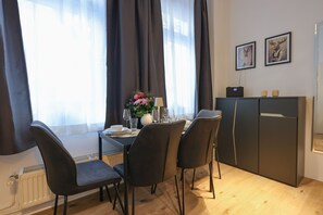 A dining area with a table set for four, a cabinet with two framed pictures, and a radiator on the wall.