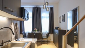 Una cocina compacta con un fregadero, una mesa de comedor con sillas, un microondas y una escalera.
