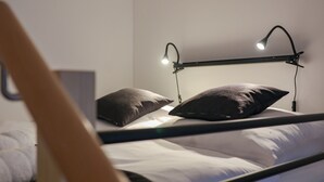 Una cama con dos almohadas y un cabecero con dos lámparas.