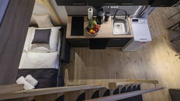 Une petite cuisine équipée avec un lit, un coin repas et un lave-linge encastré.
