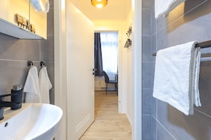 Ein modernes Badezimmer mit einem weißen Waschbecken, dunklen Fliesen und einem Handtuchhalter.