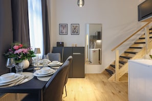 Ein moderner Essbereich mit gedecktem Tisch für zwei Personen, im Hintergrund eine Küche und eine Holztreppe.