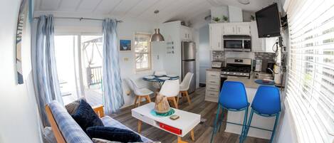 Un espacio habitable compacto con kitchenette, comedor y sofá con mesita.