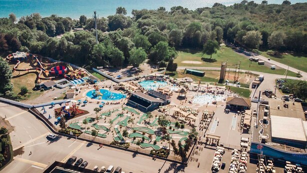 An aerial view of a resort with a pool area, water slides, and a golf course.